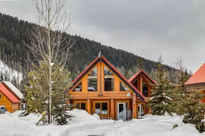 a log cabin with snow in front of a mountain at Charming Rustic Cabin Perfect for Groups in Golden