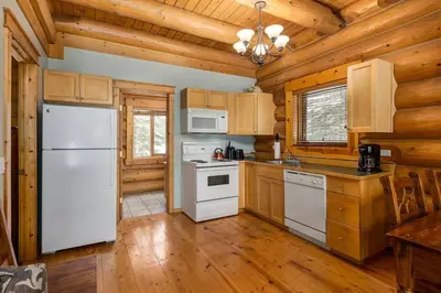 a kitchen with white appliances and wooden walls at Beautiful Rustic Chalet in the Heart of Rockies in Golden