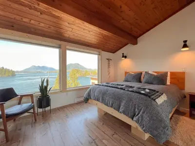 a bedroom with a large bed and a large window at Marielles Lookout - Your Oceanfront Escape Framed by Forest & Waves in Tofino