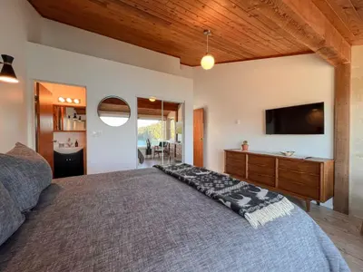 a bedroom with a large bed and a television at Marielles Lookout - Your Oceanfront Escape Framed by Forest & Waves in Tofino