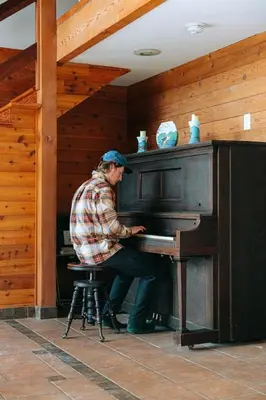 a man sitting at a piano in a room at First Light - Vintage waterfront with hot tub - One Bedroom in Tofino