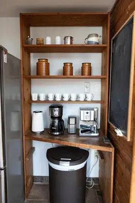 a kitchen with a shelf with a coffee maker and a coffee pot at First Light - Vintage waterfront with hot tub - One Bedroom in Tofino