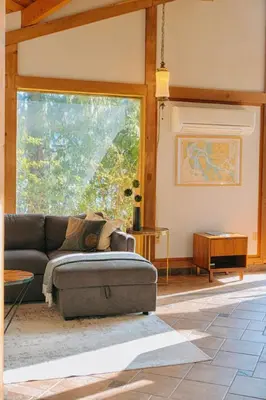 a living room with a couch and a large window at First Light - Vintage waterfront with hot tub - One Bedroom in Tofino