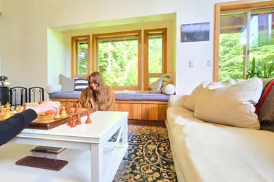 a woman is playing chess in a living room at Cedar and Salt in Tofino