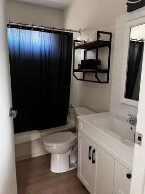 a bathroom with a toilet and a black shower curtain at Jaspers Seaside Resort complex, in Courtenay