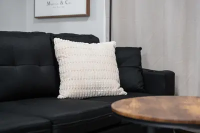 a black couch with a white pillow and a table at The Cabin Sleep in Edmonton