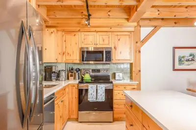 a kitchen with wooden cabinets and a refrigerator at Alpine Timbers 2 Luxury Chalet with Hot Tub in Big White