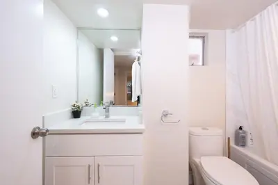 a white bathroom with a sink and a toilet at Quiet 5 BR 7 bed Escape with sunny Deck near UBC in Vancouver