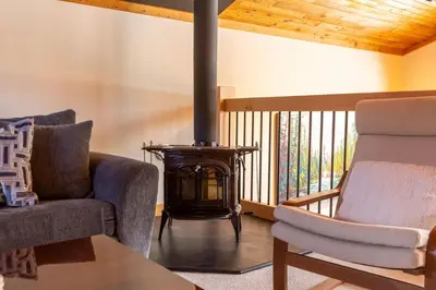 a living room with two chairs and a wood stove at Elk River Estate by Fernie Central Reservations in Fernie