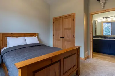 a bedroom with a wooden bed and a bathroom at Moose Lodge by Fernie Central Reservations in Fernie