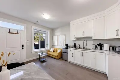 a kitchen with white cabinets and a couch in it at Private Entrance Suite Near Deer Lake & Metro in Burnaby