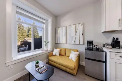 a living room with a couch and a table and a window at Private Entrance Suite Near Deer Lake & Metro in Burnaby