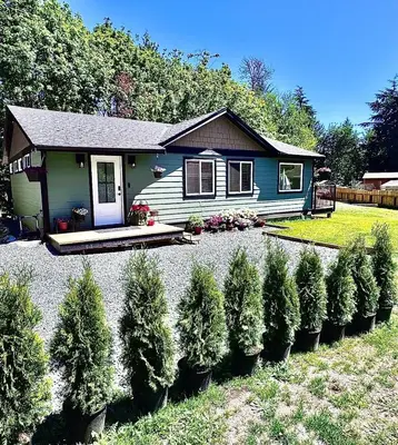 a small house with a row of trees in front of it at Harbourview Hideaway Sooke in Sooke