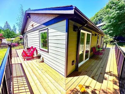 a house with a deck with red chairs on it at Harbourview Hideaway Sooke in Sooke
