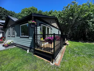 a small house with flowers in a yard at Harbourview Hideaway Sooke in Sooke