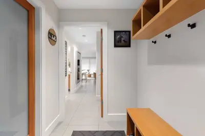 a hallway of a house with white walls and a staircase at 2BR + Sofabed | Gables | Epic Village Location | Secure Parking | Stylish & Cozy in Whistler
