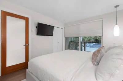 a white bedroom with a large bed and a window at 2BR + Sofabed | Gables | Epic Village Location | Secure Parking | Stylish & Cozy in Whistler