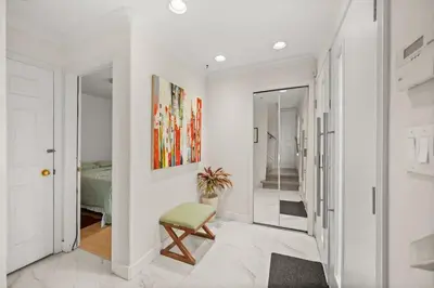 a white hallway with a chair and a bedroom at Modern & Bright 5BR Family Home in Vancouver