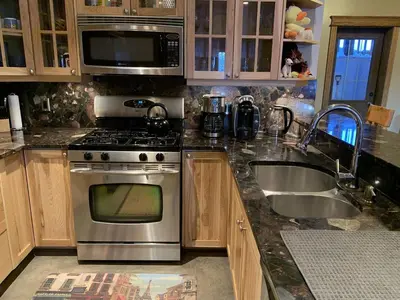 a kitchen with a stainless steel stove and a sink at Snowed Inn Chalet by Fernie Central Reservations Right on the Slopes in Fernie