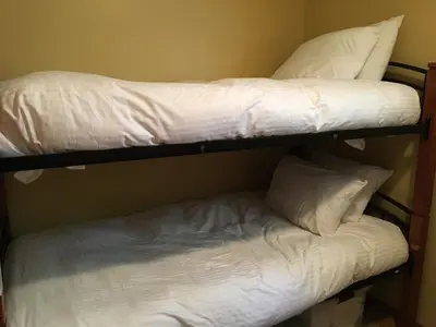 two bunk beds with white sheets and pillows at Snowed Inn Chalet by Fernie Central Reservations Right on the Slopes in Fernie