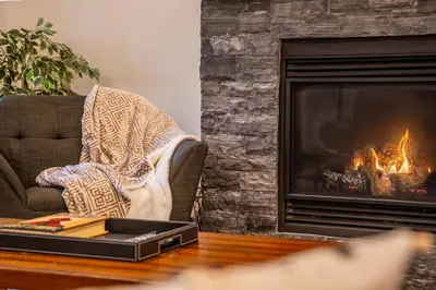 a living room with a fireplace and a laptop on a table at Alpine Chic - two-story mtn escape near downtown in Canmore