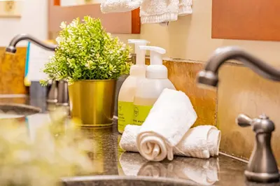 a sink with two bottles of soap and a towel at Rundle Range Retreat Lux Mtn View Condo near dt in Canmore