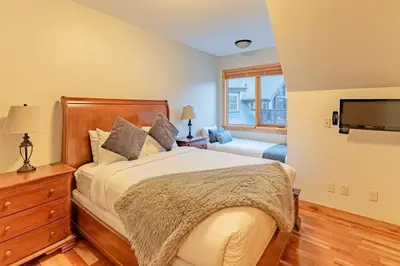 a bedroom with a large bed and a television at Rundle Range Retreat Lux Mtn View Condo near dt in Canmore