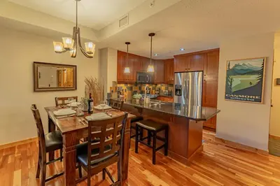 a kitchen with a large wooden table and a kitchen island at Rundle Range Retreat Lux Mtn View Condo near dt in Canmore