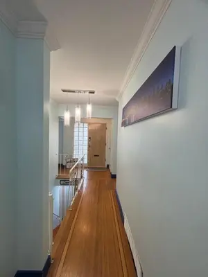 a hallway of a home with wooden floors and a painting on the wall at Charming Bright 3BR House - Upper Level Suite in Burnaby