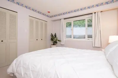 a white bedroom with a large bed and a window at Elegant Cypress Park Villa with Panoramic Ocean View in West Vancouver