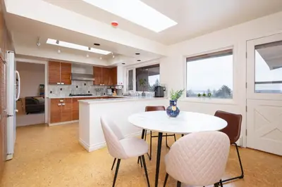a kitchen and dining room with a white table and chairs at Elegant Cypress Park Villa with Panoramic Ocean View in West Vancouver