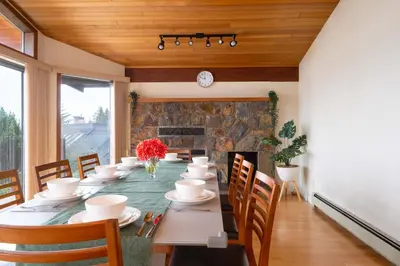 a dining room with a table and chairs and a fireplace at Elegant Cypress Park Villa with Panoramic Ocean View in West Vancouver