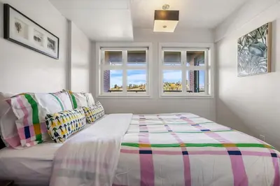 a bedroom with a bed and two windows at Stylish & Romantic Riverside Stay in Downtown in Calgary
