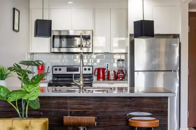 a kitchen with white cabinets and a stainless steel refrigerator at Stylish & Romantic Riverside Stay in Downtown in Calgary
