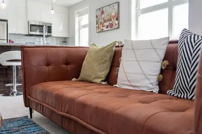 a brown couch with pillows on it in a living room at Cozy And Modern 2 Bedroom Along Bow River in Downtown in Calgary