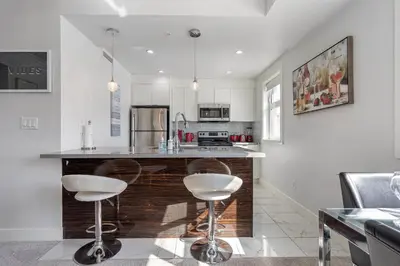 a kitchen with a counter and two stools at Cozy And Modern 2 Bedroom Along Bow River in Downtown in Calgary