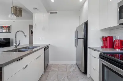 a kitchen with white cabinets and a stainless steel refrigerator at Delightful 2 BR And 2 Bath Water View in Downtown in Calgary