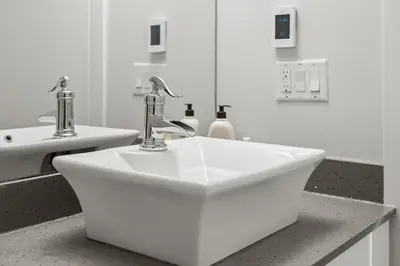 a white sink with two faucets in a bathroom at Waterfront 2 Beds And 2 Bath Downtown Urban Escape in Calgary