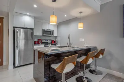 a kitchen with a bar with chairs and a refrigerator at Vibrant Stylish, Cozy Waterfront Downtown in Calgary