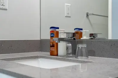 a kitchen counter with a sink with bottles on it at Vibrant Stylish, Cozy Waterfront Downtown in Calgary