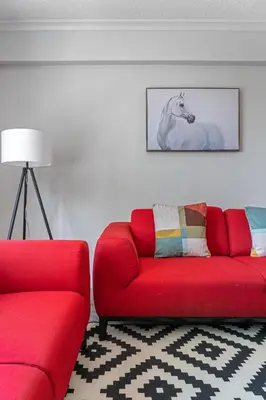 a living room with a red couch and a white horse picture at Vibrant Stylish, Cozy Waterfront Downtown in Calgary