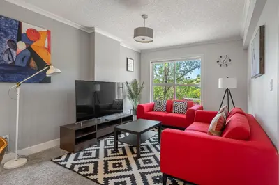 a living room with red furniture and a flat screen tv at Vibrant Stylish, Cozy Waterfront Downtown in Calgary