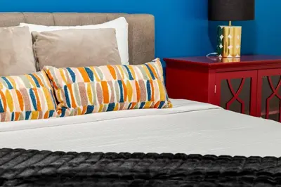 a bed with two pillows on it with a red table at Cozy 3BR unit with Arcade in the heart of Calgary in Calgary