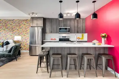 a kitchen with pink walls and a large island with stools at Cozy 3BR unit with Arcade in the heart of Calgary in Calgary