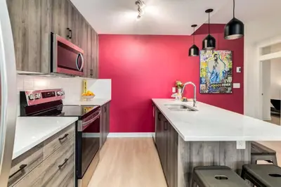 a kitchen with red walls and a white counter top at Cozy 3BR unit with Arcade in the heart of Calgary in Calgary
