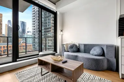 a living room with a couch and a large window at Modern 1BR City Escape with Balcony near DT Calgary in Calgary