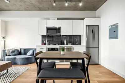 a kitchen and living room with a table and chairs at Modern 1BR City Escape with Balcony near DT Calgary in Calgary