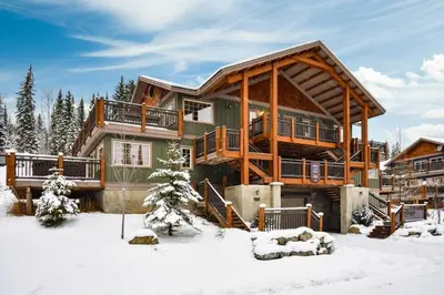 a large log cabin in the snow with snow covered at Rockies Escape Skiing Hiking and Private Hot Tub in Golden
