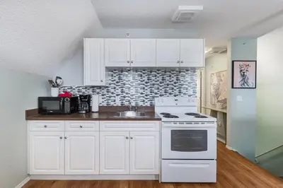 a kitchen with white cabinets and a white stove top oven at The Cutest Condo in Canmore and Banff in Canmore