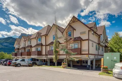 a large building with cars parked in a parking lot at Cozy Mountain View Condo Close to DT Canmore in Canmore